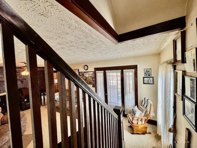 stairway featuring carpet, a textured ceiling, and baseboards