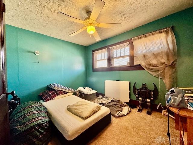 bedroom with ceiling fan, a textured ceiling, and carpet flooring