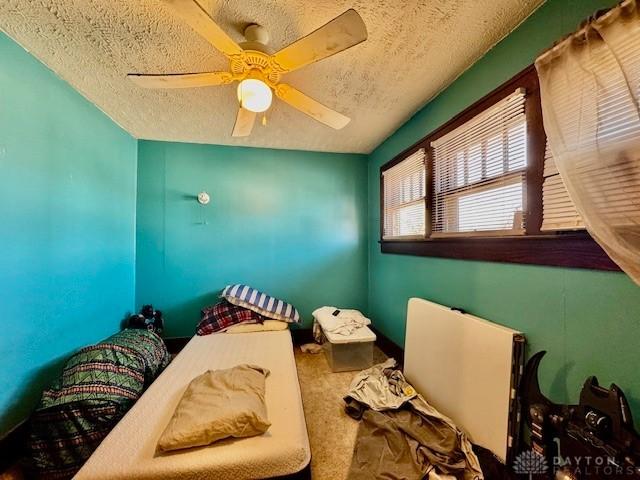 miscellaneous room with a textured ceiling, ceiling fan, and carpet flooring