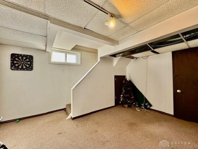 below grade area with carpet flooring, a paneled ceiling, and baseboards