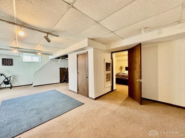 basement with baseboards, a drop ceiling, and carpet flooring