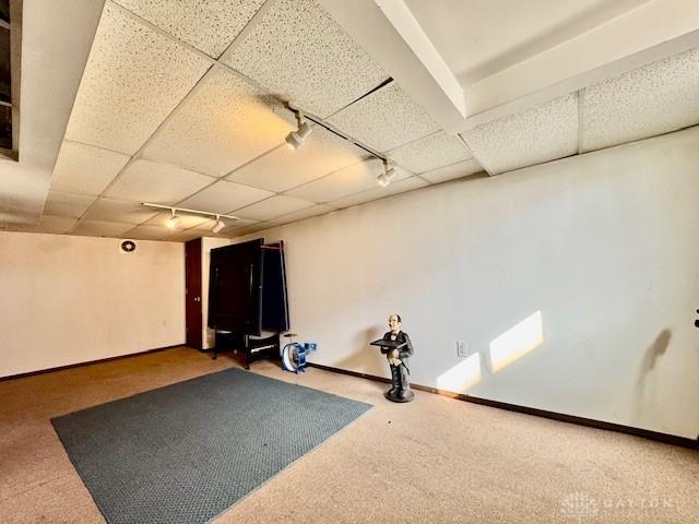 interior space featuring baseboards, carpet floors, a drop ceiling, and track lighting