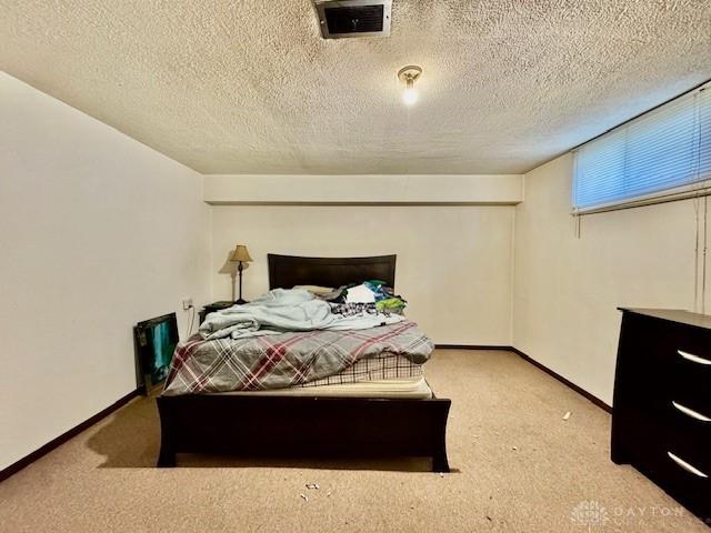 bedroom with baseboards, a textured ceiling, visible vents, and carpet flooring