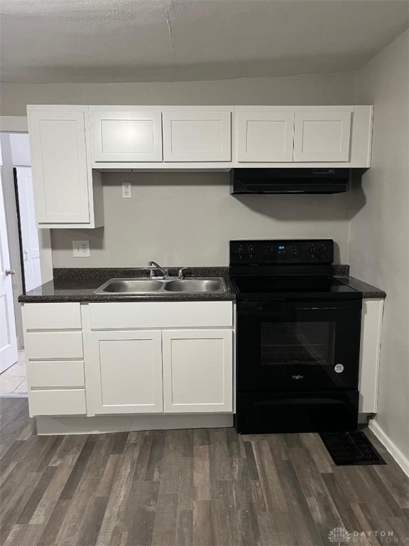 kitchen featuring dark wood finished floors, black electric range oven, white cabinets, a sink, and under cabinet range hood