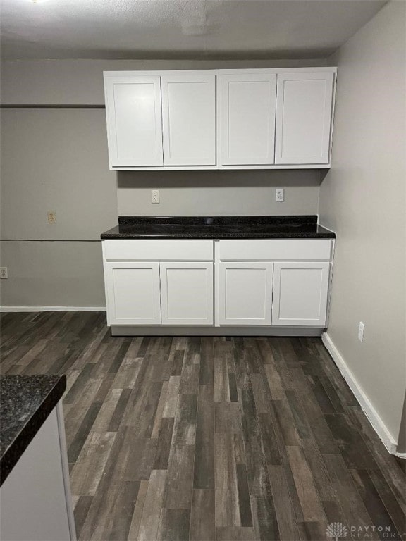 kitchen featuring dark wood-type flooring, white cabinetry, and baseboards