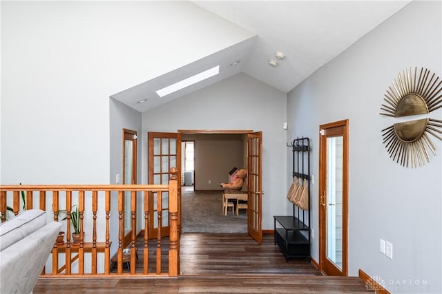 hallway featuring a skylight, baseboards, wood finished floors, french doors, and high vaulted ceiling