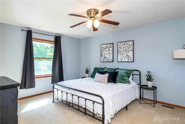 carpeted bedroom with a ceiling fan, visible vents, and baseboards