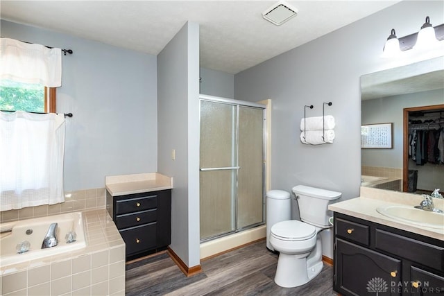 full bathroom featuring toilet, wood finished floors, a garden tub, vanity, and a shower stall