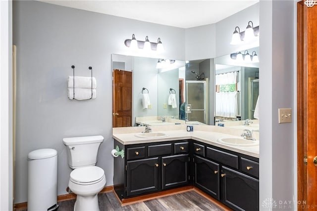 bathroom with double vanity, a sink, toilet, and a shower stall