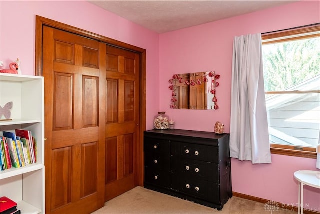 bedroom with baseboards, a textured ceiling, and light colored carpet