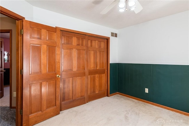 bedroom with light carpet, visible vents, a closet, and wainscoting