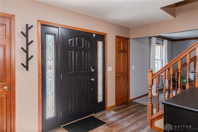 entryway with visible vents, stairway, baseboards, and wood finished floors