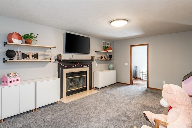 living room featuring visible vents, baseboards, a glass covered fireplace, carpet, and a textured ceiling