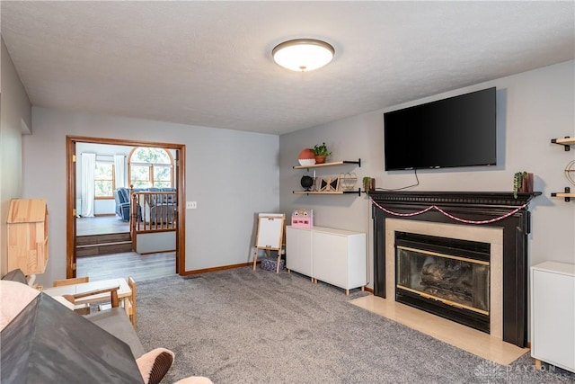 living area featuring a textured ceiling, carpet floors, a fireplace with flush hearth, and baseboards