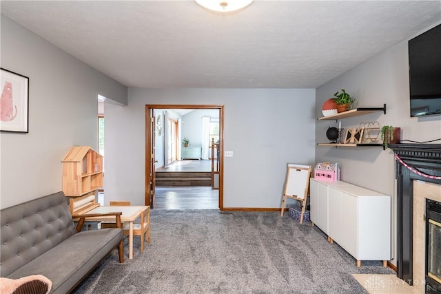 interior space with a fireplace with flush hearth, baseboards, a textured ceiling, and light colored carpet