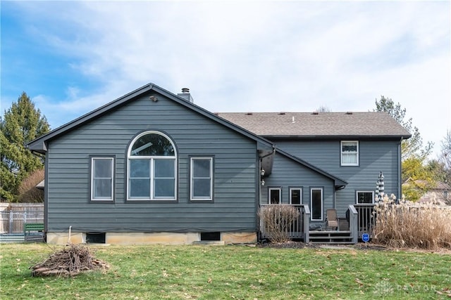 rear view of property featuring a yard, a wooden deck, and fence