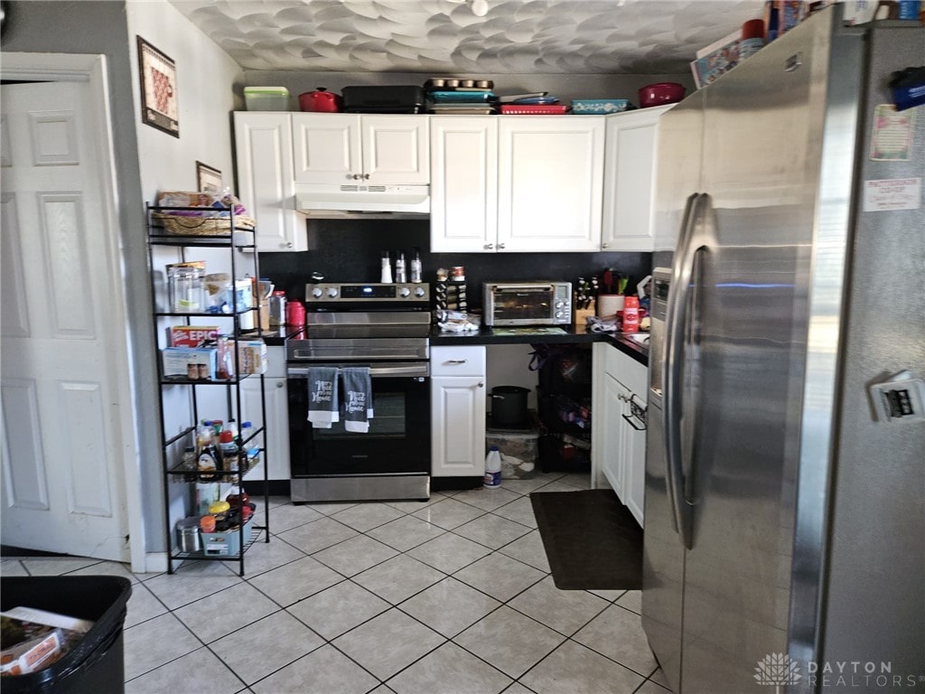 kitchen with dark countertops, under cabinet range hood, white cabinetry, and appliances with stainless steel finishes