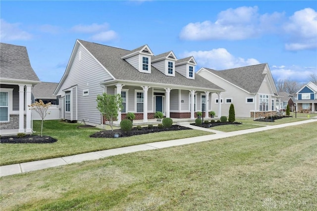 view of front of house with a front yard, covered porch, and roof with shingles