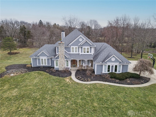 traditional-style home with a chimney, a shingled roof, and a front yard