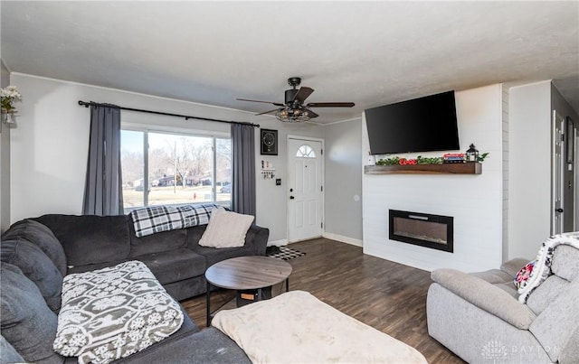 living area featuring ceiling fan, baseboards, wood finished floors, and a glass covered fireplace