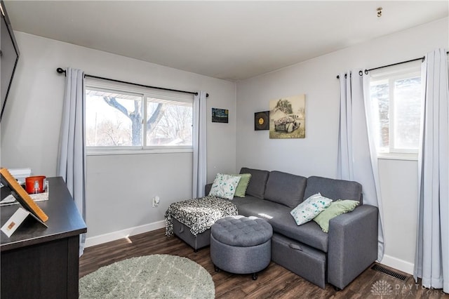 living area with baseboards, visible vents, and dark wood-type flooring