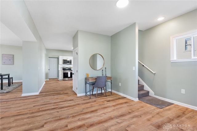 interior space featuring stainless steel appliances, white cabinetry, baseboards, light wood-style floors, and decorative backsplash