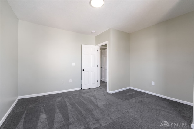 empty room with dark carpet and baseboards