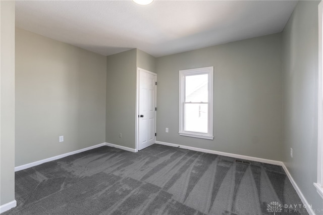 empty room with visible vents, baseboards, and dark colored carpet