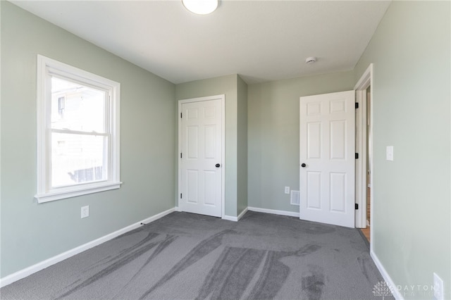 unfurnished bedroom with dark colored carpet and baseboards