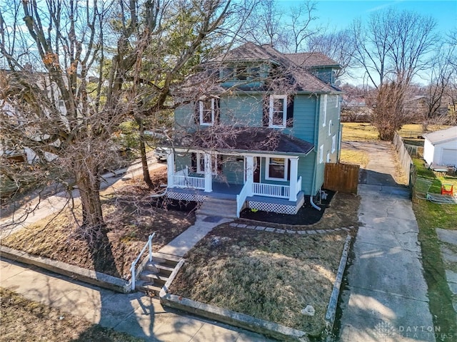 american foursquare style home featuring a porch and roof with shingles