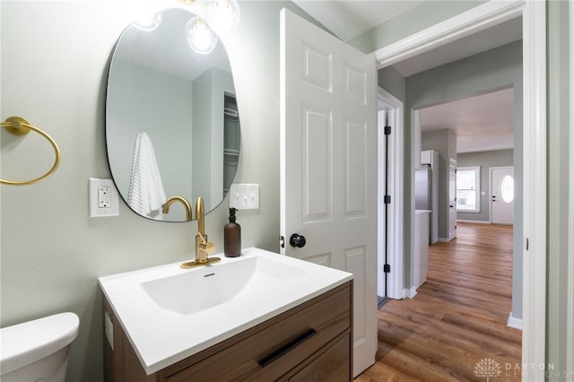 bathroom featuring baseboards, vanity, toilet, and wood finished floors