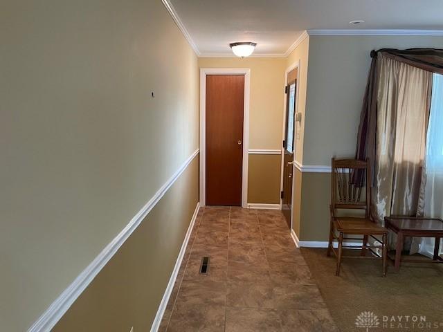 corridor featuring baseboards, visible vents, and crown molding