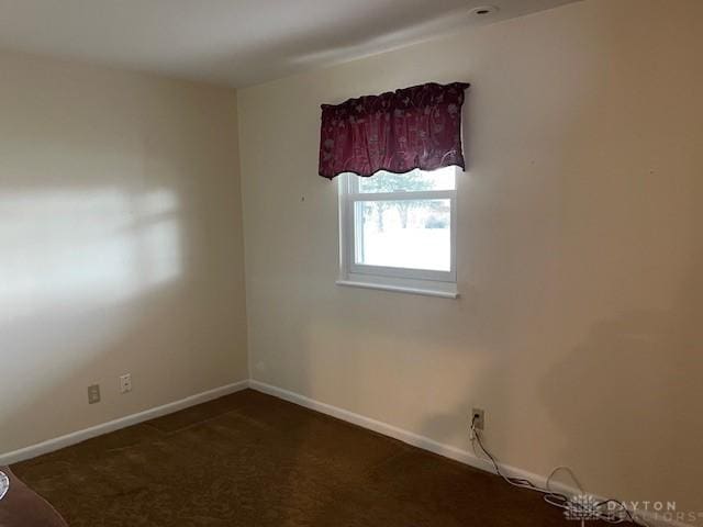 spare room featuring carpet flooring and baseboards