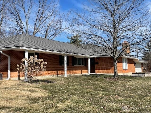 ranch-style house with a front yard, a chimney, and brick siding