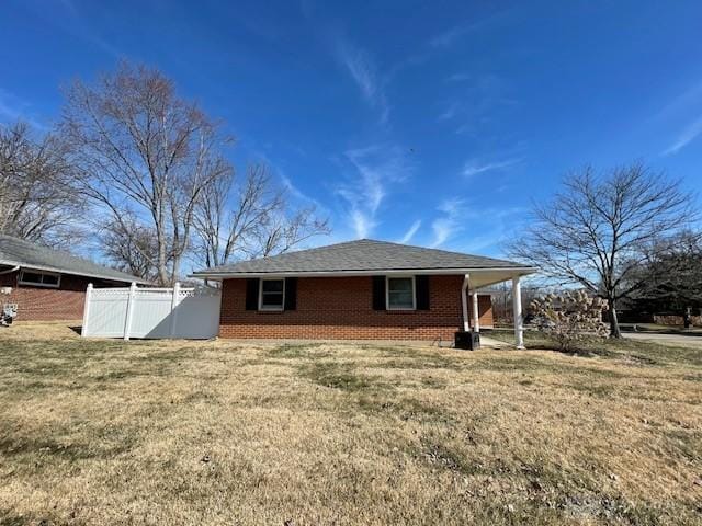 view of side of property with a yard, brick siding, and fence