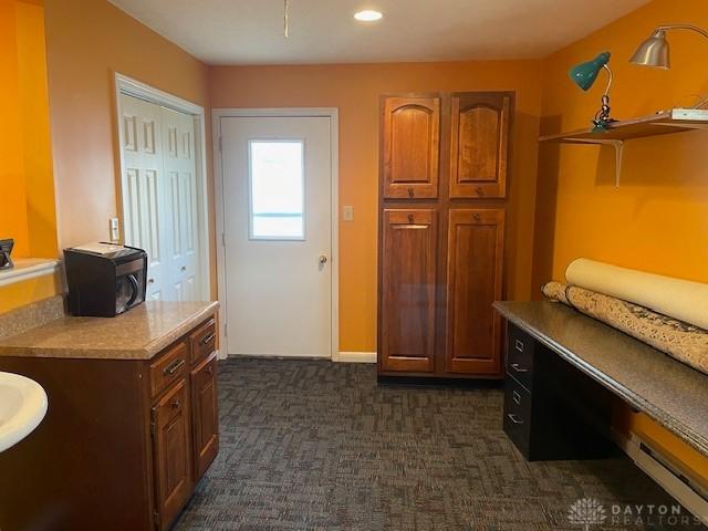 interior space featuring a baseboard heating unit and dark carpet