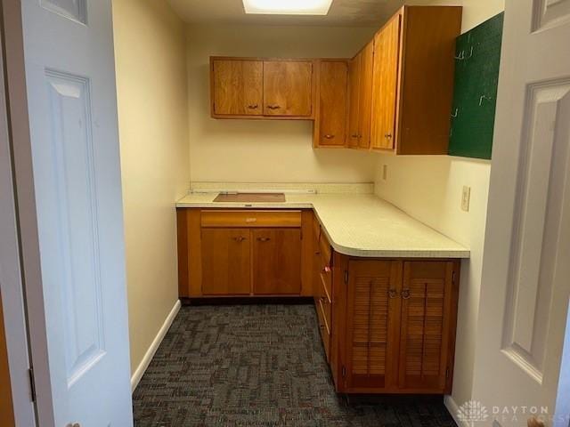 kitchen with baseboards, brown cabinets, and light countertops