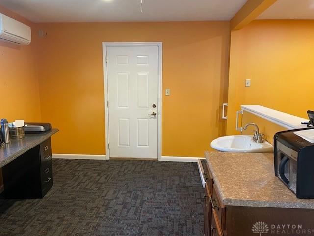 interior space featuring a wall unit AC, a sink, and baseboards