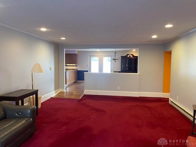 living room with a baseboard radiator, recessed lighting, baseboards, dark colored carpet, and crown molding