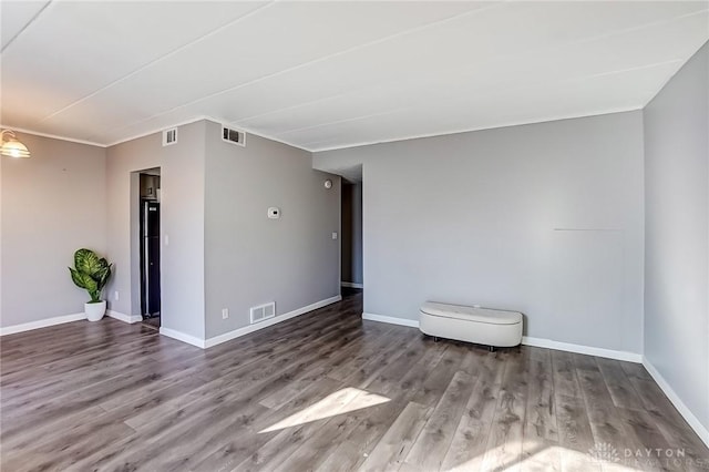 unfurnished room featuring wood finished floors, visible vents, and baseboards