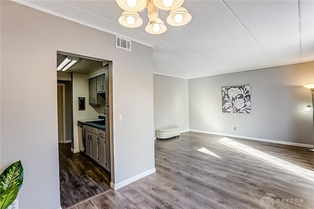 interior space featuring dark wood-style flooring, visible vents, a notable chandelier, and baseboards