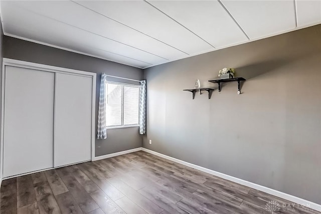 unfurnished bedroom featuring a closet, baseboards, and wood finished floors