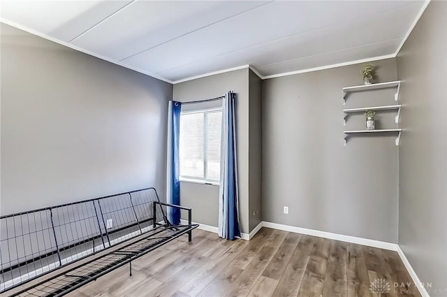 spare room featuring ornamental molding, baseboards, and wood finished floors