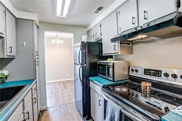 kitchen featuring visible vents, light wood-style flooring, stainless steel appliances, under cabinet range hood, and a sink