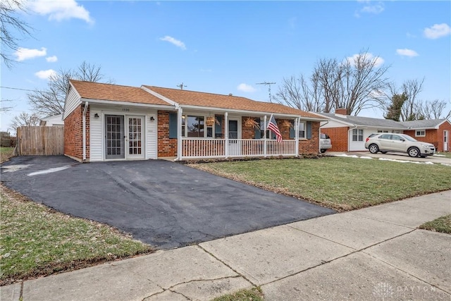 ranch-style house with aphalt driveway, a front yard, covered porch, and brick siding