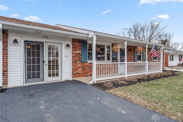 view of front of house featuring brick siding and a porch