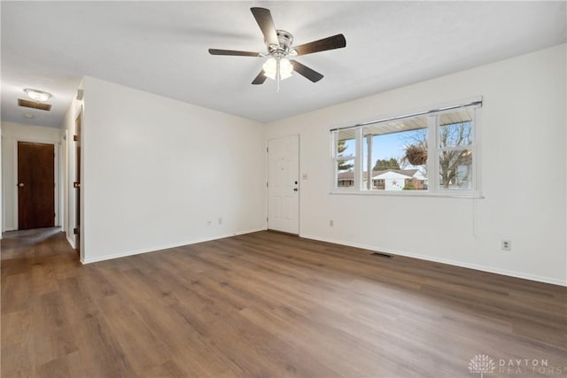 spare room with a ceiling fan, visible vents, baseboards, and wood finished floors