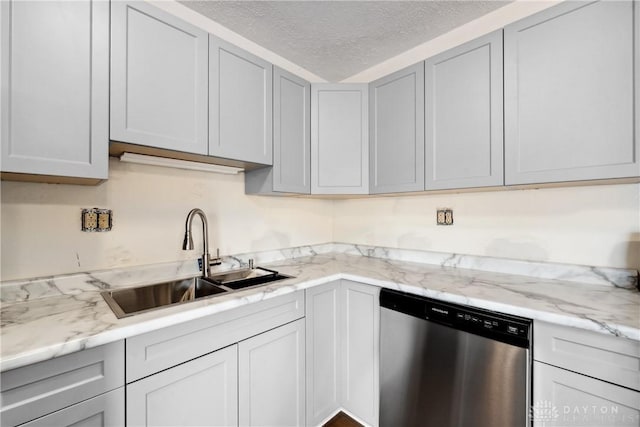 kitchen with a textured ceiling, stainless steel dishwasher, a sink, and light stone counters