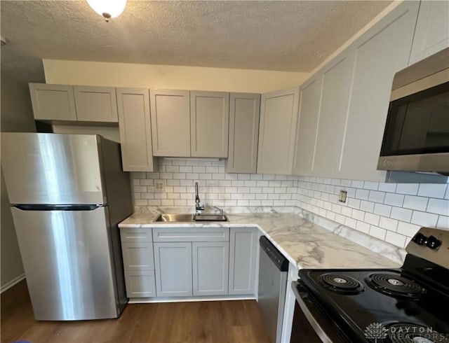 kitchen featuring stainless steel appliances, dark wood-style flooring, a sink, and gray cabinetry