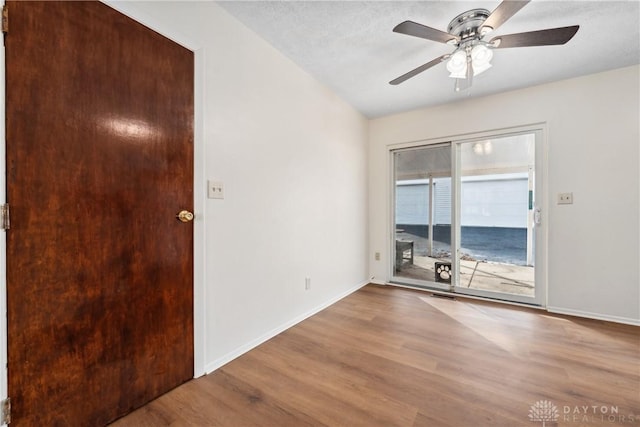 spare room with a ceiling fan, visible vents, baseboards, and wood finished floors